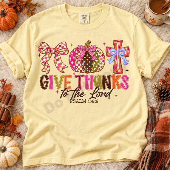 Give Thanks to the Lord DTF transfer with a patchwork checkered bow, plaid and polka dot pumpkin, colorful patterned cross, and Psalm 136:6 lettering Shown on a Butter t-shirt.