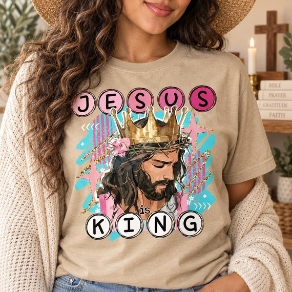 Jesus is King DTF transfer with painterly portrait of Jesus wearing a golden crown over a crown of thorns, teal brushstrokes, pink florals, and circle-letter text Shown on a Sandstone t-shirt.