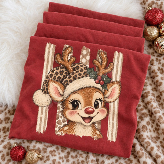 Cartoon fawn wearing a leopard-print Santa hat with cream fur trim and holly sprig, set against a rustic striped background DTF transfer Shown on a Chili t-shirt.