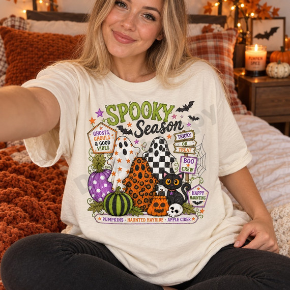 Spooky Season Halloween DTF transfer with star-print and leopard-print ghosts, checkered ghost, polka-dot and striped pumpkins, a jack-o-lantern, black cat, skull, bats, and signpost-style badge lettering reading Ghosts Ghouls & Good Vibes, Tricky or Treat, Boo Crew, and Happy Haunting Shown on a Ivory t-shirt.