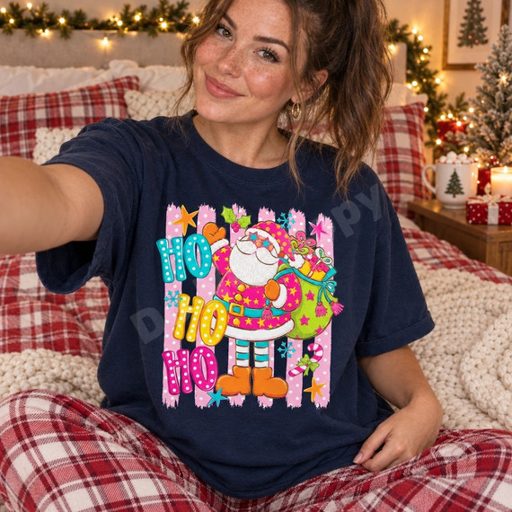 Neon pink Santa Claus DTF transfer with polka-dot hat, star sunglasses, and bold stacked HO HO HO lettering on a pink striped background Shown on a True Navy t-shirt.