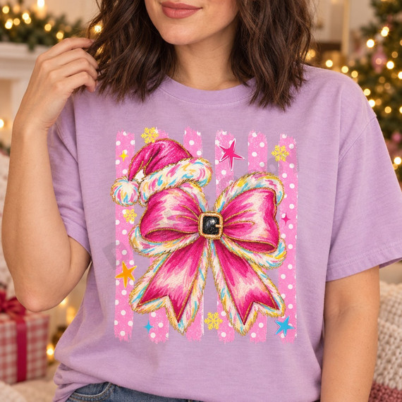 Pink Santa hat and glittery pink bow DTF transfer with black belt buckle center, stars, snowflakes, and polka-dot stripe background on a lavender shirt Shown on a Orchid t-shirt.
