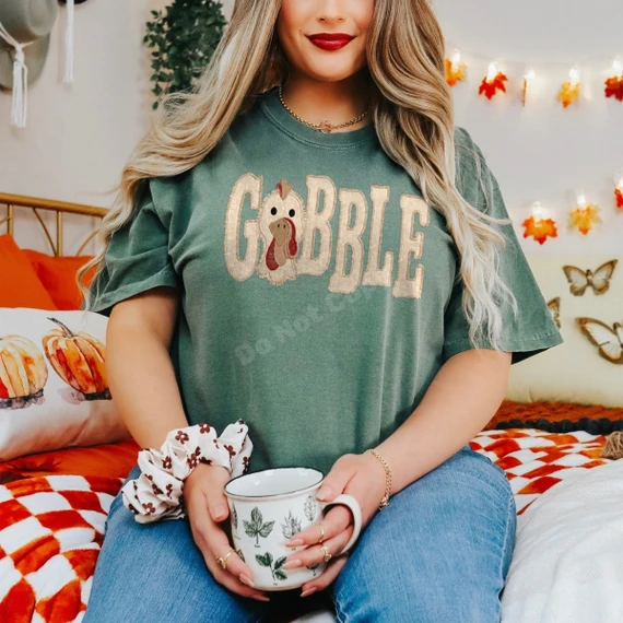 Gobble Thanksgiving DTF transfer with varsity-style tan lettering and turkey face illustration on a green t-shirt