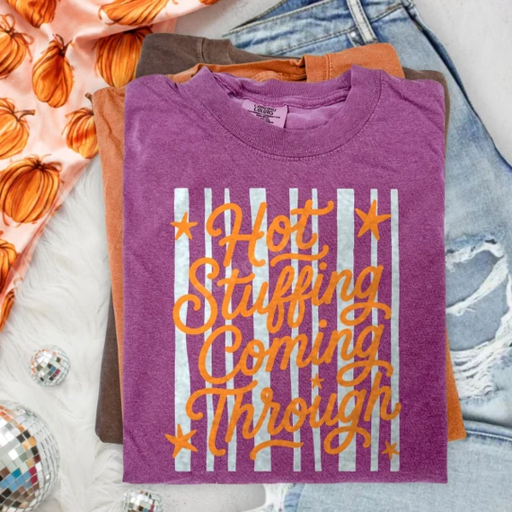Hot Stuffing Coming Through DTF transfer with orange retro script lettering, stars, and vertical stripes on a purple shirt