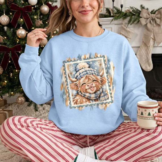 Winter Highland cow DTF transfer with knit hat and scarf, snowflakes, and a vintage postage stamp style frame