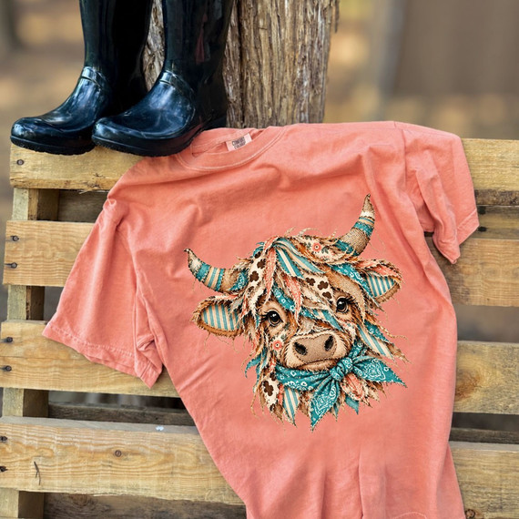 Highland cow DTF transfer with quilted patchwork fabric design, floral and bandana print patterns, and turquoise bandana accent on a pink shirt