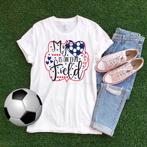 My Heart Is On That Field Soccer Sublimation Transfer T-Shirt, displayed with jeans, sneakers, and a soccer ball on green artificial grass.