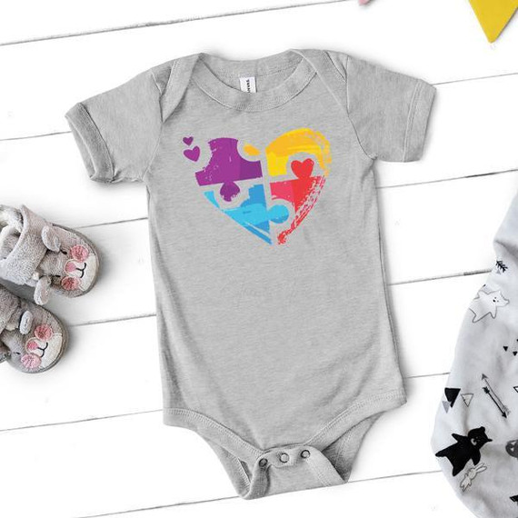 Puzzle Heart Autism Awareness FINAL STOCK-INFANT, a gray infant onesie featuring a colorful puzzle piece heart screen print heat transfer.