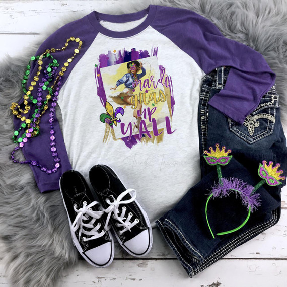 Mardi Gras Up Y'all Sublimation Transfer, colorful Mardi Gras themed design on a casual outfit with purple and white long sleeve shirt, decorated with Mardi Gras beads, sunglasses, and accessories.