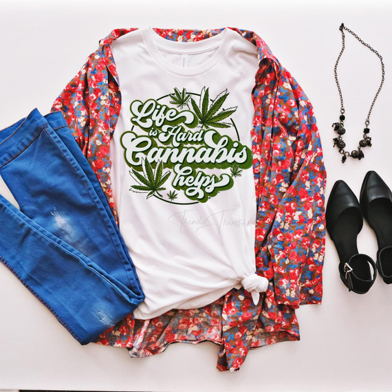 Life is Hard Cannabis Helps Sublimation Transfer, product T-shirt with cannabis leaf design and phrase on white background, styled with jeans, floral kimono, necklace, and black shoes.