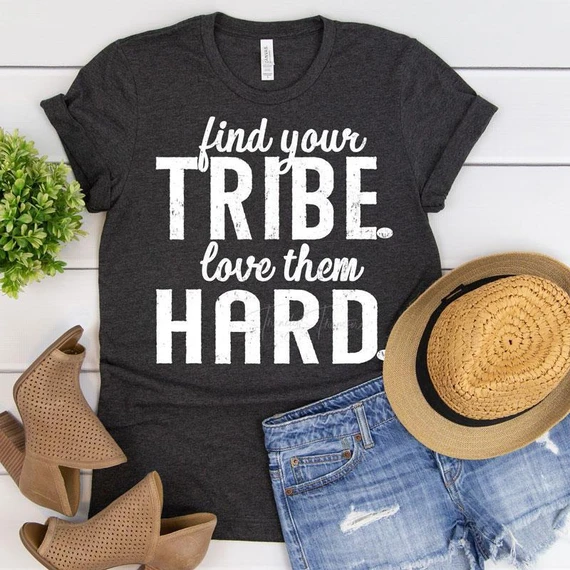 Find Your Tribe Love Them Hard White Screen Print Transfer, white text on a dark grey t-shirt with casual accessories and a plant, showcasing a motivational quote design.