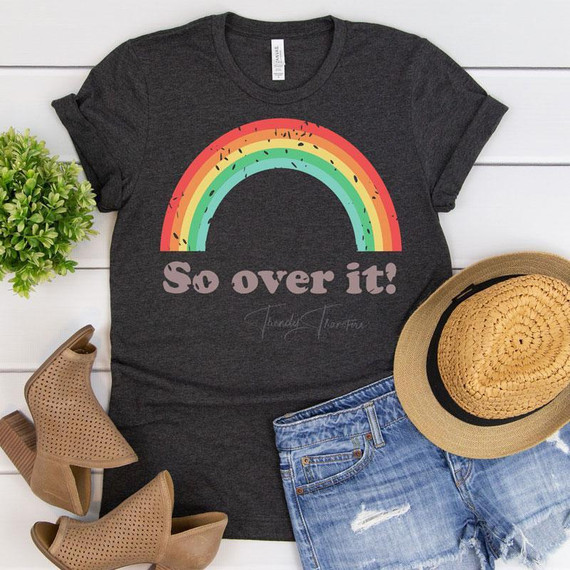 So Over It! Screen Print Heat Transfer, black T-shirt with rainbow design and text, casual outfit with distressed denim shorts, tan hat, and beige ankle boots.