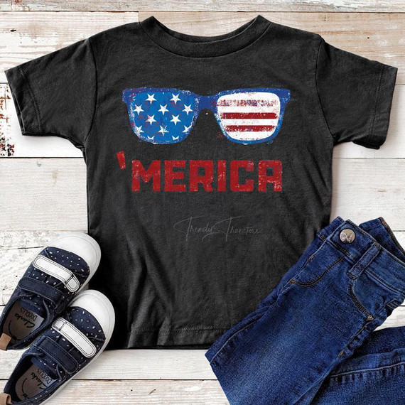 Merica Sunglasses YOUTH Screen Print Heat Transfer, black T-shirt with patriotic sunglasses design and 'I MERICA' text, paired with jeans and sneakers.