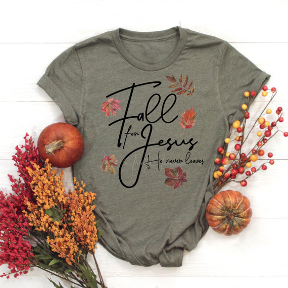 Fall for Jesus He Never Leaves Screen Print Transfer, gray T-shirt with fall leaves design and inspirational message, surrounded by pumpkins and autumn flowers for seasonal decoration