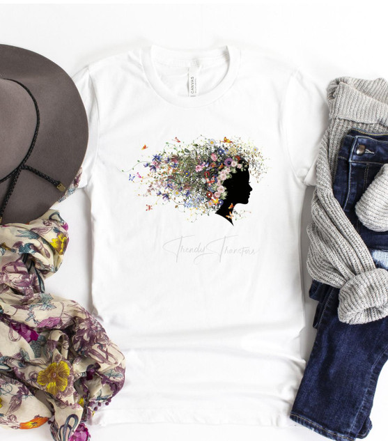 Wildflowers Soul Sublimation Transfer, product image showing a t-shirt with a floral silhouette of a woman with colorful wildflowers and butterflies, surrounded by accessories like a hat, scarf, and denim jeans.
