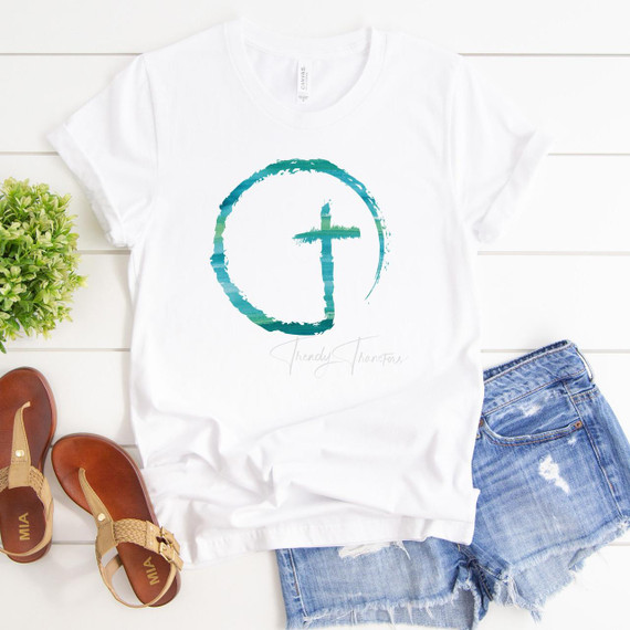 Watercolor Cross Circle Sublimation Transfer, product image of a white t-shirt with a watercolor-style circular cross design in teal and green colors.
