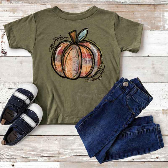 Tie Dye Pumpkin YOUTH Screen Print Heat Transfer, image of a youth t-shirt featuring a colorful pumpkin graphic with tie dye effect, paired with blue jeans and sneakers on a wooden surface.