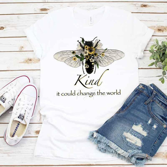 Be Kind It Could Change The World Sublimation Transfer T-shirt with bee and floral design, white casual tee, next to denim shorts and white sneakers, on wooden background
