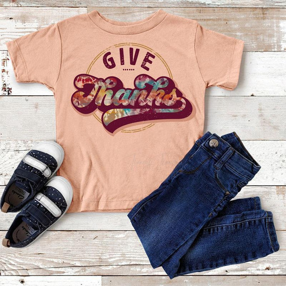 Give Thanks Tie Dye Youth Screen Print Heat Transfer, colorful tie dye design with the message 'Give Thanks' on a peach youth T-shirt, paired with dark jeans and sneakers.