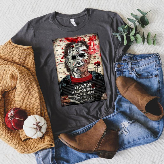 Halloween Horror Men Screen Print Heat Transfer, spooky horror-themed graphic on a dark gray T-shirt featuring a creepy mask and blood splatters, displayed with jeans, boots, a knitted blanket, and small pumpkins.