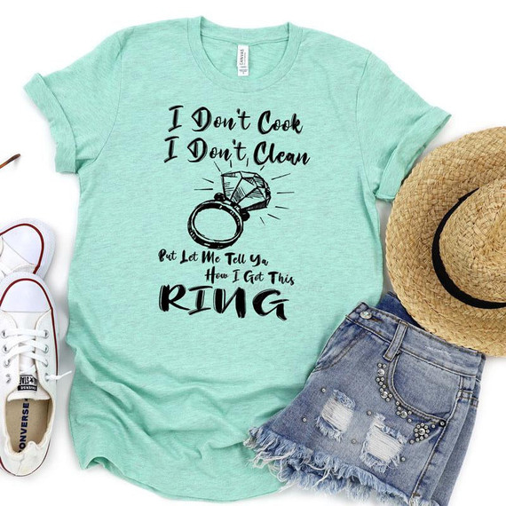 I Don't Cook I Don't Clean FINAL STOCK Screen Print Heat Transfer T-shirt, light green casual shirt with playful text and a ring illustration, paired with denim shorts, white sneakers, and a straw hat.