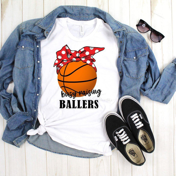 Busy Raising Ballers Basketball Sublimation Transfer, graphic T-shirt with basketball illustration and red polka dot bandana, laid on a flat surface with denim jacket, sunglasses, and sneakers.
