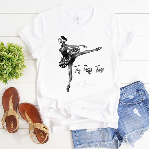 Tiny Pretty Things Sublimation Transfer, artistic ballet dancer design on white t-shirt with the text 'Tiny Pretty Things' and casual denim shorts and sandals.