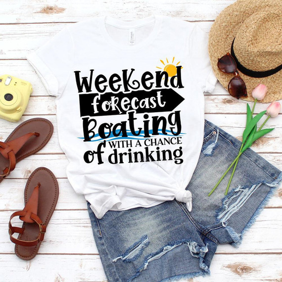 Weekend Forecast Boating With a Chance of Drinking sublimation transfer, product t-shirt with a boat-themed design, laid out with accessories like sandals, sunglasses, a hat, and flowers.