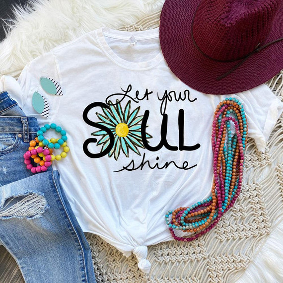 Let Your Soul Shine Sublimation Transfer, white T-shirt with colorful daisy design and text, surrounded by accessories including a pink hat, beaded jewelry, and distressed jeans.