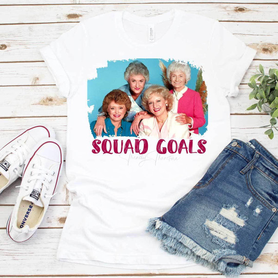Squad Goals Golden Girls Sublimation Transfer T-shirt with a graphic of the Golden Girls and the text 'Squad Goals' on a white background, laid out with casual apparel and accessories.