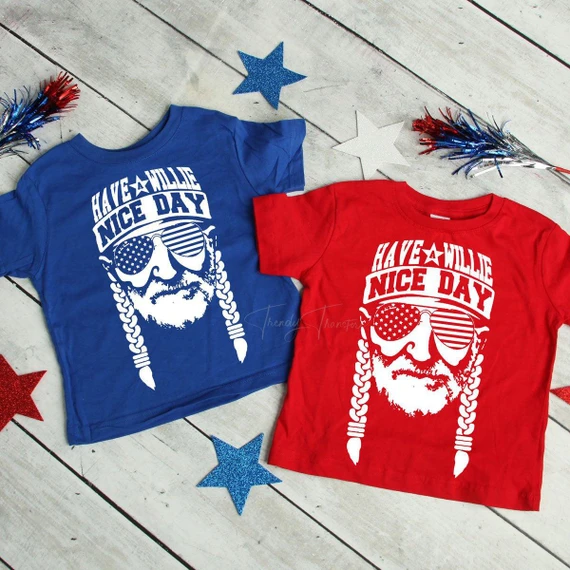 Have a Willie Nice Day Youth Screen Print Heat Transfer, blue and red T-shirts with a graphic of a bearded man wearing star-spangled sunglasses, surrounded by red and blue star decorations.