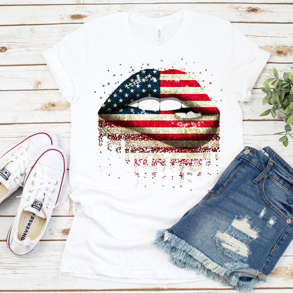 Patriotic Dripping Lip Bite USA Red White and Blue Flag Sublimation Transfer, graphic t-shirt with abstract American flag lips design with red, white, and blue stripes and stars, on white t-shirt laid on wooden surface with sneakers and denim shorts.