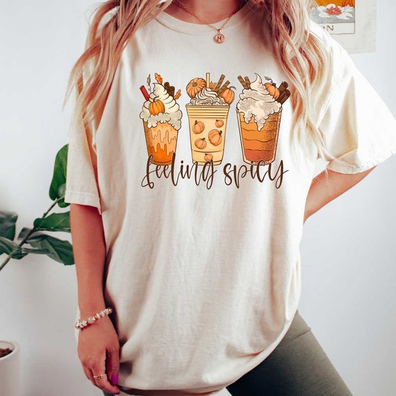 Feeling Spicy DTF Heat Transfer, illustrated graphic of three whipped cream-topped fall-themed drinks with pumpkins and cinnamon sticks, with 'feeling spicy' text below on a t-shirt.