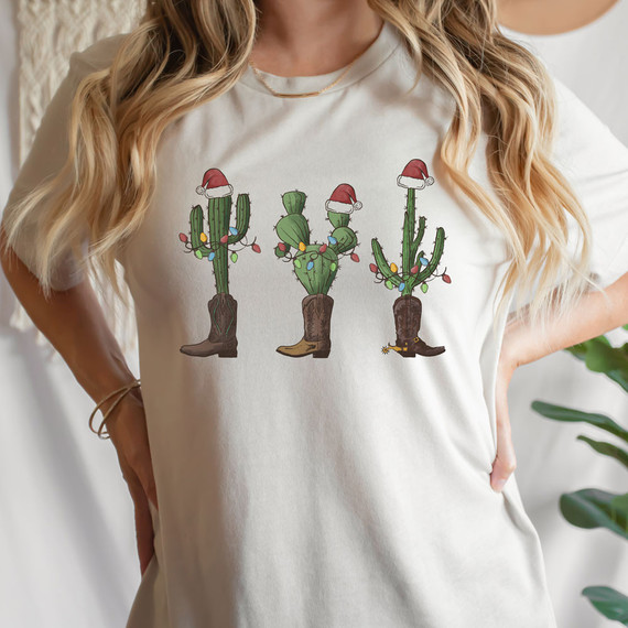 Christmas Cactuses Screen Print Heat Transfer, festive cactus design wearing cowboy boots and Santa hats, decorated with Christmas lights on a white t-shirt.