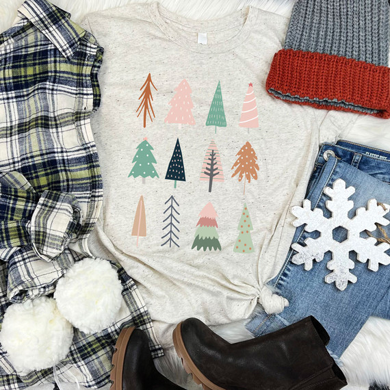 Boho Christmas Trees DTF Transfer, colorful Christmas tree designs on a casual gray T-shirt, surrounded by winter fashion accessories like plaid shirt, knitted hat, jeans with snowflake patch, white pom-pom slippers, and black boots.