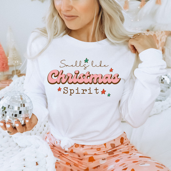 Smells Like Christmas Spirit Screen Print Transfer, festive holiday graphic with Christmas-themed text on a white sweatshirt worn by a woman celebrating Christmas.