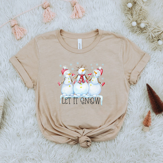 Let It Snow Snowman DTF Transfer, festive winter-themed design on a beige t-shirt featuring three cheerful snowmen with 'Let It Snow' text.