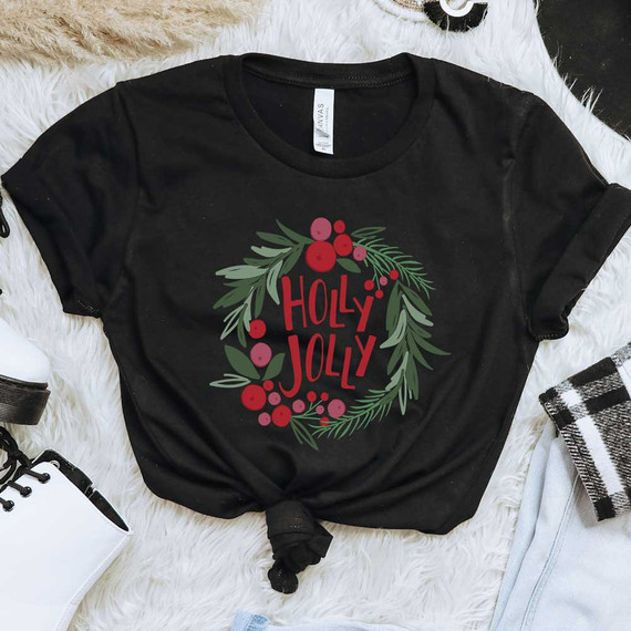 Holly Jolly Wreath DTF Heat Transfer, black T-shirt with festive red and green holiday design featuring the text Holly Jolly surrounded by holly leaves and berries.