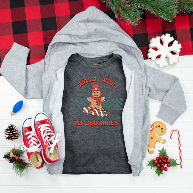 Rollin With My Doughmies DTF Heat Transfer, holiday themed graphic t-shirt with gingerbread man on skateboard, surrounded by Christmas decorations and sneakers.