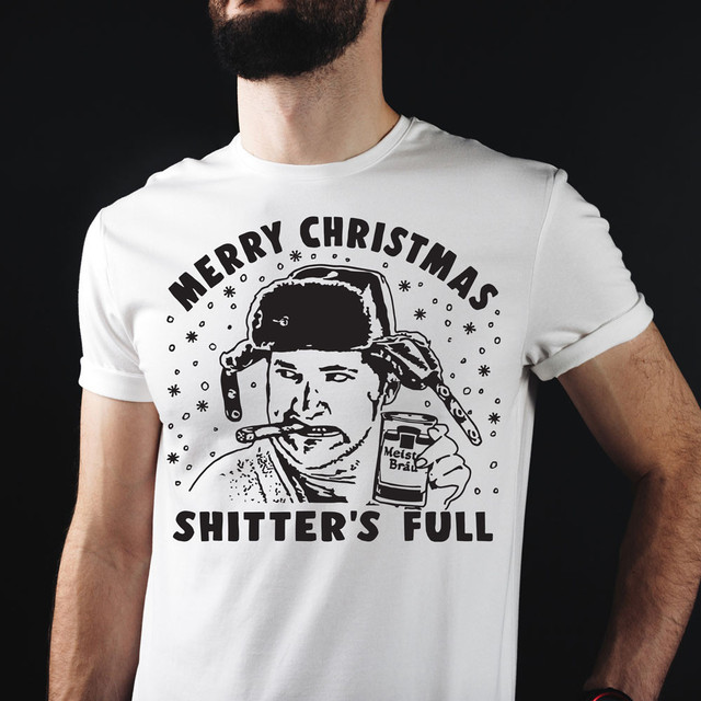 Merry Christmas Shitter's Full Cousin Eddie DTF Heat Transfer, humorous graphic t-shirt featuring a cartoonish image of a man in winter attire holding a beer and a cigarette, with holiday-themed text and snowflake accents.