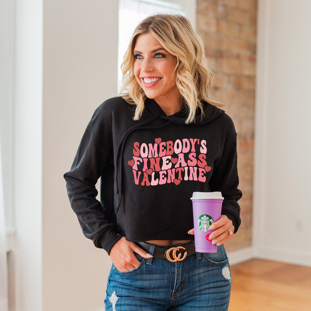 Somebody's Fine Ass Valentine DTF Heat Transfer, close-up of a smiling woman wearing a black hoodie with pink and red lettering and holding a purple Starbucks cup.