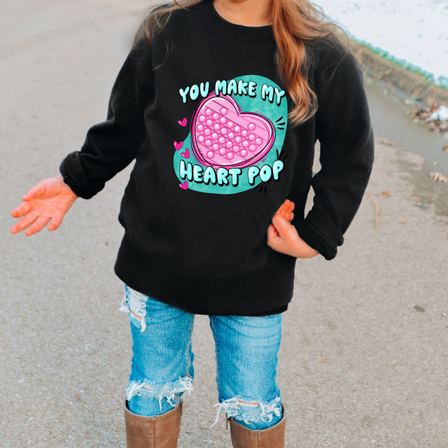 You Make My Heart Pop Pink DTF Heat Transfer, product image showing a black sweatshirt with a colorful pink heart-shaped pop-it graphic and playful lettering on the front.
