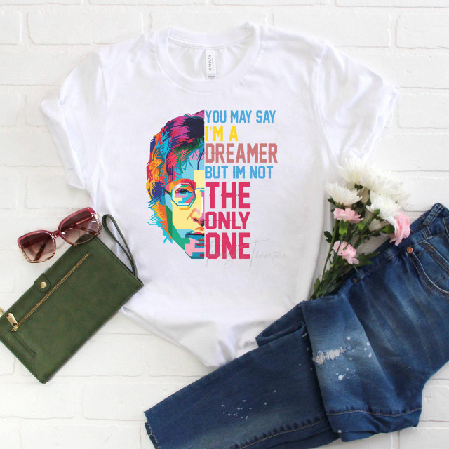 Lennon You May Say I'm a Dreamer Subway Art Pop Art Fan Art Sublimation Transfer, a colorful graphic t-shirt featuring a stylized portrait of John Lennon alongside the quote 'You May Say I'm a Dreamer but I'm not the Only One' displayed on a white background, styled with jeans, sunglasses, and flowers.