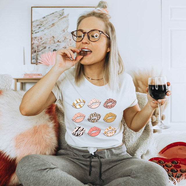 Lips DTF Heat Transfer, woman enjoying chocolate and wine in a cozy living room showing off her lips printed T-shirt with kiss marks.