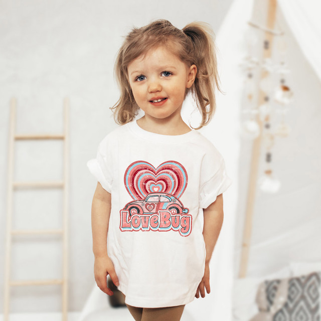 Lovebug Heart Sublimation Transfer, a colorful sublimation transfer with love bug design and heart motifs on a white t-shirt worn by a young girl.