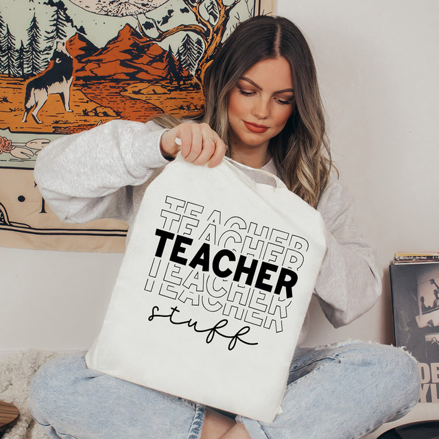 Teacher Stuff DTF Heat Transfer, woman holding a tote bag with 'Teacher Stuff' design, indoor setting.