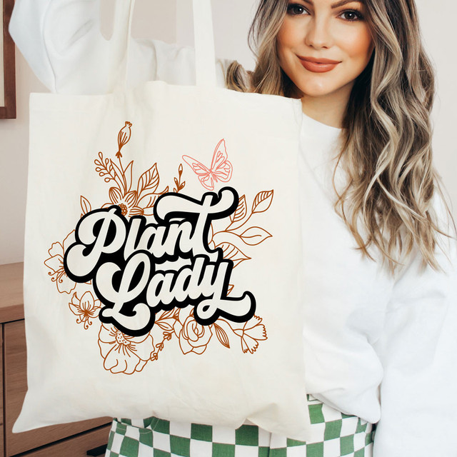 Plant Lady DTF Heat Transfer, woman holding tote bag with floral design and text 'Plant Lady' for customizing with heat transfer technology.