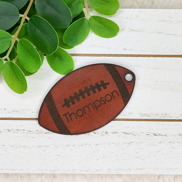 Personalized Leather Football Keychain, brown leather keychain shaped like a football with customizable name 'Thompson'.