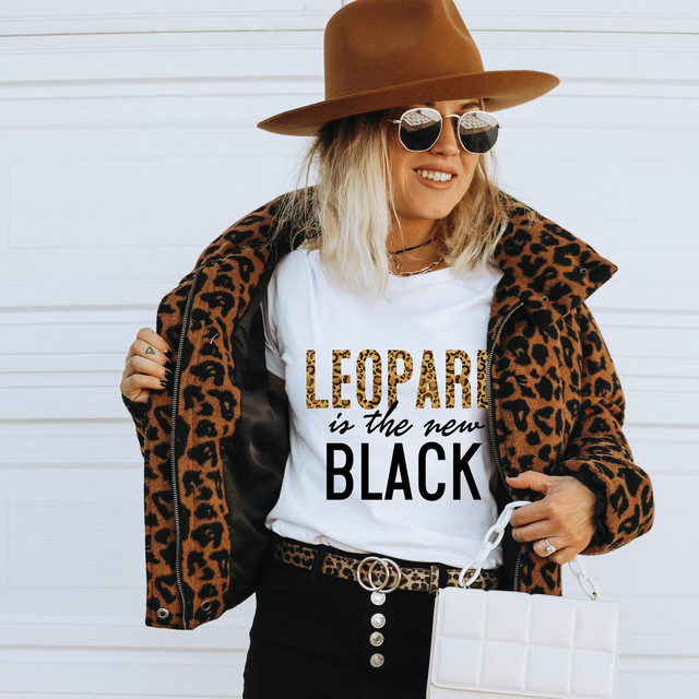 Leopard Is The New Black DTF Heat Transfer, fashionable woman wearing animal print jacket and sunglasses with a white T-shirt showcasing the leopard print text design.