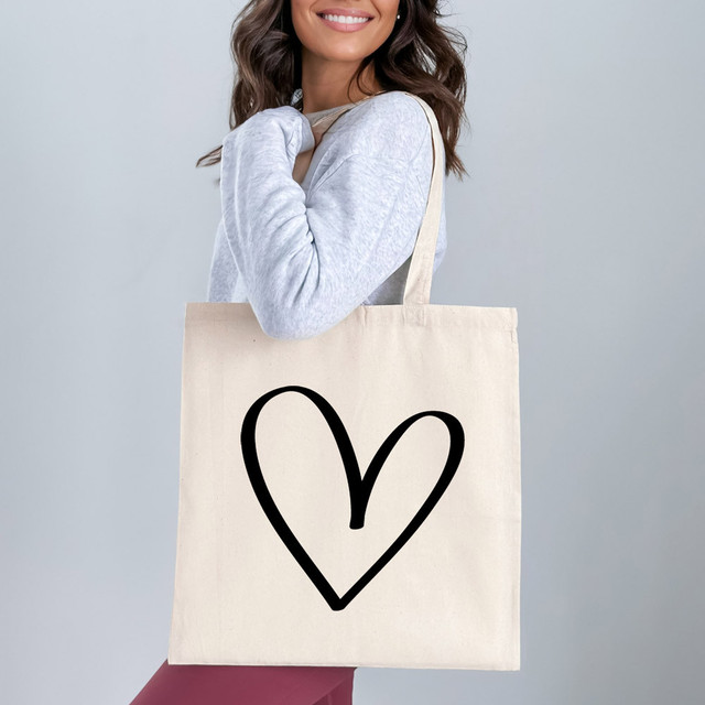 Heart Outline DTF Heat Transfer, a black heart outline design printed on a beige tote bag.